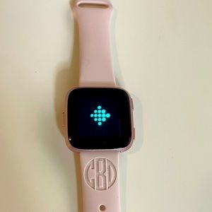 Rose gold Fitbit versa with accessories